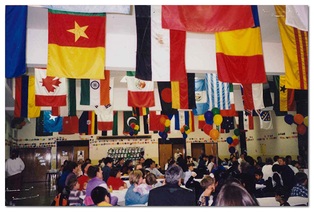 Color photograph of at least 42 national flags hanging from the ceiling in the cafeteria at Greenbriar West. 